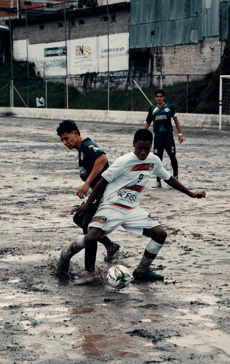 Players engage in a passionate soccer game on a muddy field, showcasing skill and determination.